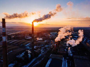Günbatımında sanayi manzarası, hava manzarası. Fabrika bacalarından duman çıkıyor..