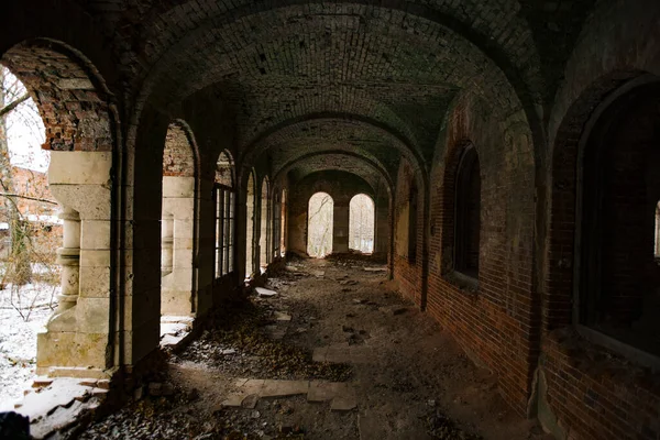 Dark corridor of old ancient abandoned red brick ruined historical building.