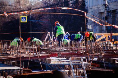 Workers in protective helmets are repairing bridge in Voronezh.
