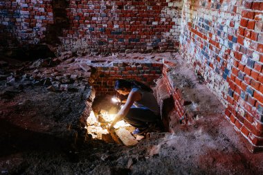 El feneriyle arkeolog kilisenin altındaki eski mahzeni inceliyor..