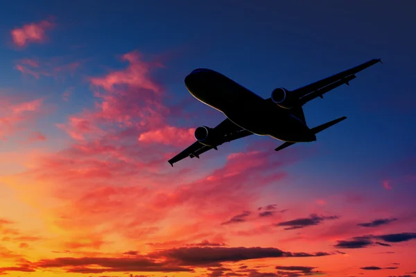 Silhouette d'avion dans le ciel au coucher du soleil Images De Stock Libres De Droits