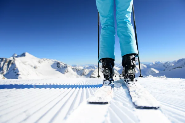 Menina no esqui de pé na neve fresca na pista de esqui recém-preparado no dia ensolarado nas montanhas Fotos De Bancos De Imagens Sem Royalties