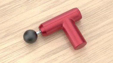 Tahta masadaki kırmızı masaj tabancası.