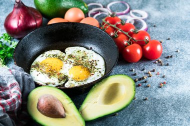 Kızarmış yumurta tavada ve avokadoda, tomano grinin üstünde.