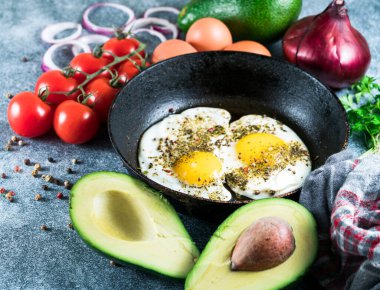 Kızarmış yumurta tavada ve avokadoda, tomano grinin üstünde.
