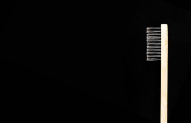 Çevre dostu antibakteriyel bambu ahşap diş fırçası. Siyah arka planda beyaz tüyleri var..