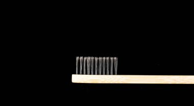 Çevre dostu antibakteriyel bambu ahşap diş fırçası. Siyah arka planda beyaz tüyleri var..