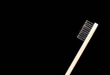 Çevre dostu antibakteriyel bambu ahşap diş fırçası. Siyah arka planda beyaz tüyleri var..