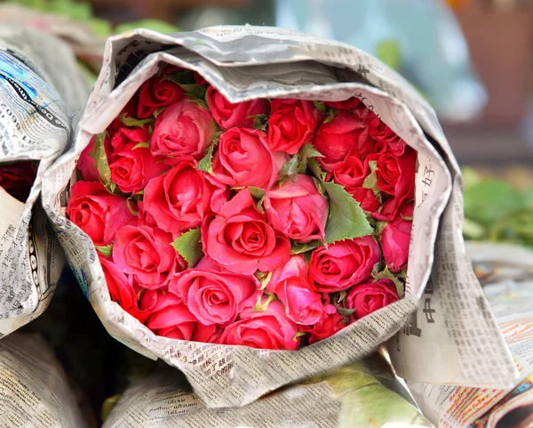 Красные розы завернутые в газету — стоковое фото