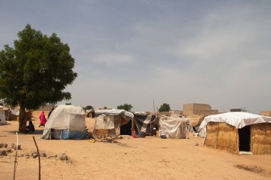 Afrika 'nın Sahra-altı kesimindeki mülteci kampı. Yerel malzemeler ve plastik çarşaflardan yapılmış kötü bir barınak..  