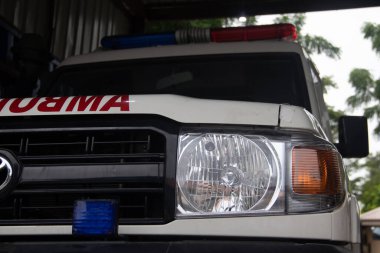 Acil tıbbi yardım için ambulans aracını kapatın. Görünür kırmızı haç, acil durum ışıkları ve siren.