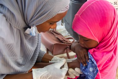 Afrika 'daki mülteci kampında 9 yaşın altındaki çocuklara rutin aşılama yapan bir tıp işçisi. 