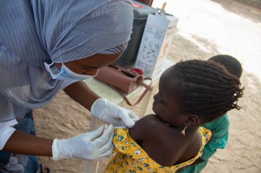 Medical worker doing routine immunization vaccination in refugee camp in Africa  clipart