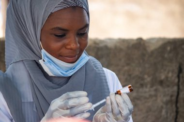 Birincil sağlık tesisinde çalışan kadın doktor kitle aşılama kampanyası için aşı hazırlıyor.