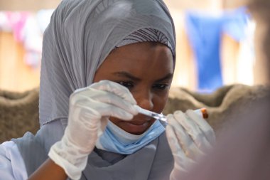 Birincil sağlık tesisinde çalışan kadın doktor kitle aşılama kampanyası için aşı hazırlıyor.