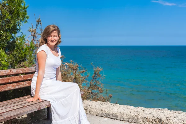 Woman sitting on the bench by the blue sea — Stock Photo, Image