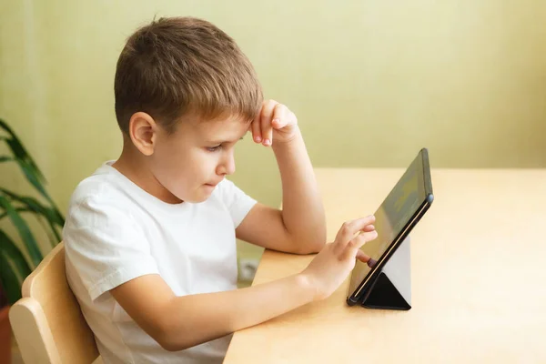 Anak sekolah yang lucu melakukan pekerjaan rumah dengan komputer di rumah — Stok Foto