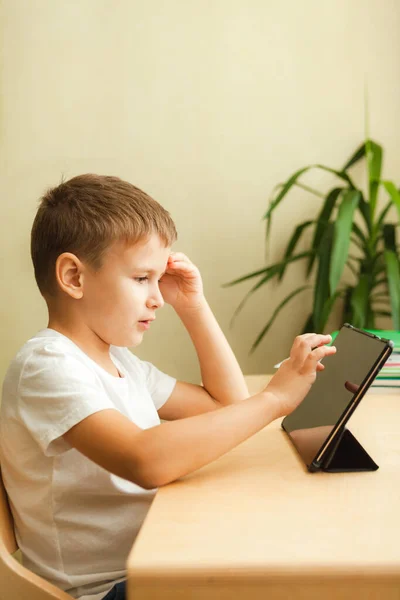 可爱的孩子坐在桌子旁边用平板电脑做作业 — 图库照片