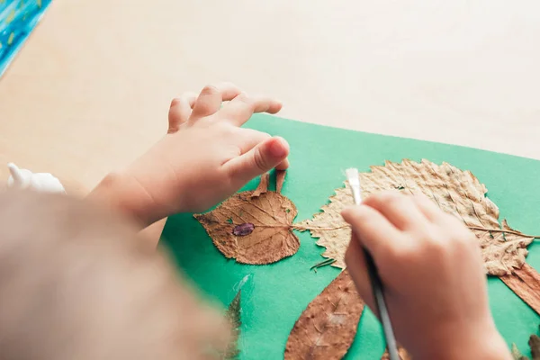 Anak glues sebuah apliksi terbuat dari daun musim gugur — Stok Foto