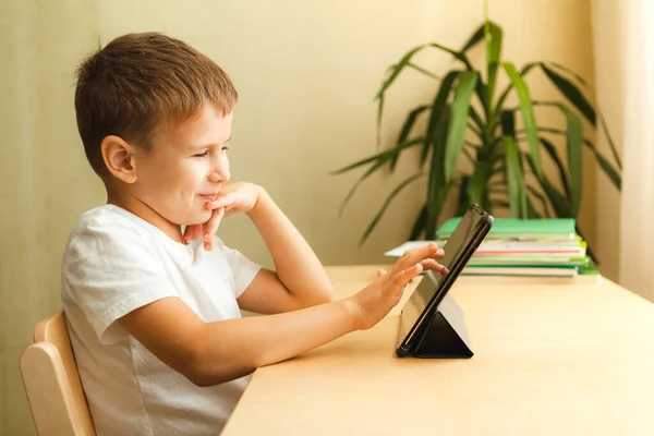 Happy child drawing on tablet sitting by desk — Stok Foto