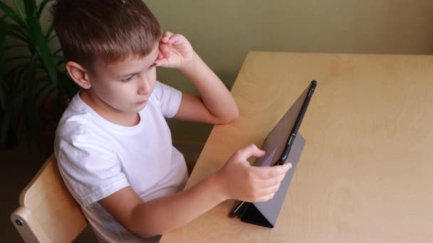 귀여운 자녀가 집에 책상 옆에 놓여 있는 태블릿을 사용하는 모습 — 비디오