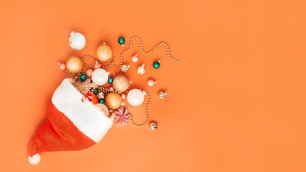 Dekorasi Natal jatuh dari topi santa di latar belakang oranye — Stok Foto