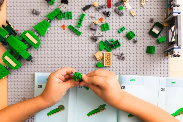 Tangan anak mengumpulkan konduktor Lego sesuai dengan instruksi — Stok Foto