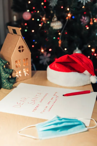 Secretária com carta ao Papai Noel e árvore de Natal decorada no fundo — Fotografia de Stock
