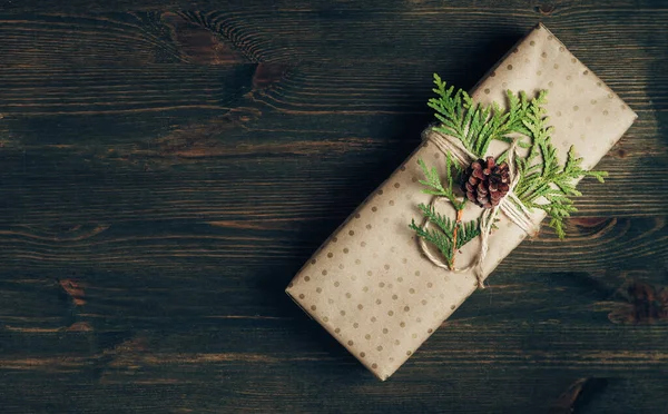 Caja de regalo envuelta en papel artesanal y decorada con rama de ciprés verde —  Fotos de Stock