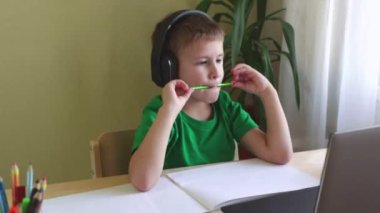 Tatlı çocuk masada oturur ve bilgisayara bakar. Karantina sırasında online ders.