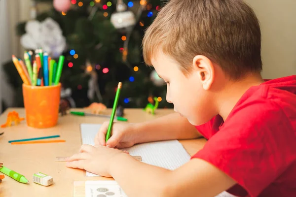 7 yaşında yaşlı bir çocuk masada oturuyor ve ödevlerini yapıyor. — Stok fotoğraf