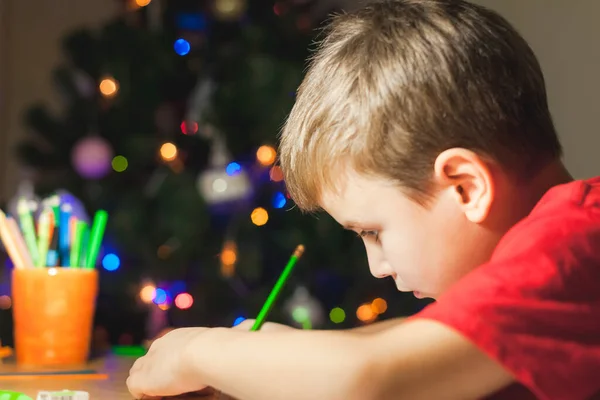 7 jaar oude jongen zitten aan het bureau en het doen van huiswerk — Stockfoto