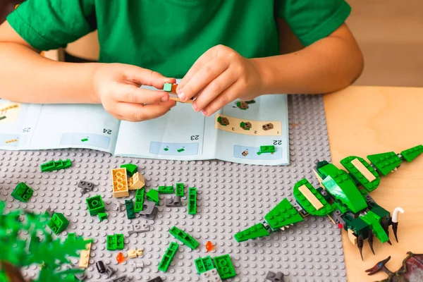 Tangan anak mengumpulkan konduktor Lego sesuai dengan instruksi — Stok Foto