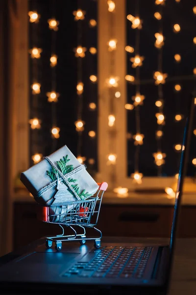 Online winkelen concept. Miniatuur winkelwagen met geschenkdoos op laptop — Stockfoto