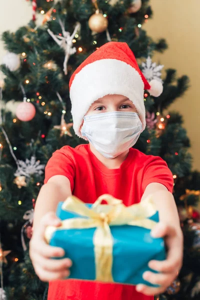 Jongen geeft geschenkdoos, focus op het heden. Gedecoreerde kerstboom op achtergrond — Stockfoto