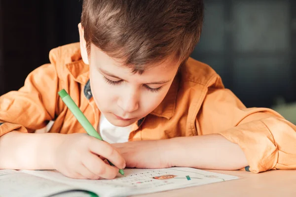 Schattig 7 jaar oud kind doen zijn huiswerk zitten door bureau — Stockfoto