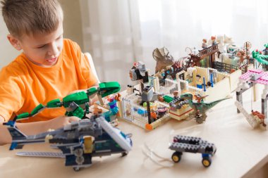 Masanın başında oturan lego tuğlalarıyla oynayan çocuk.