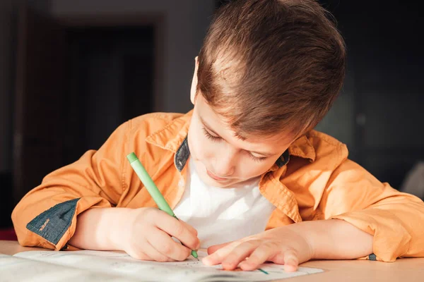 Mignon 7 ans enfant faire ses devoirs assis par bureau — Photo