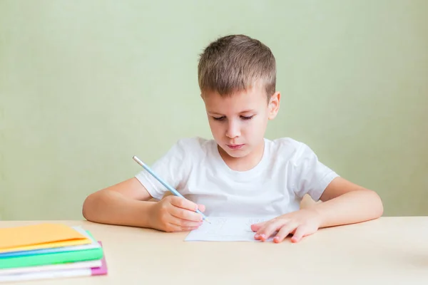Kind sitzt am Schreibtisch und erledigt schriftliche Aufgaben im Notizbuch — Stockfoto