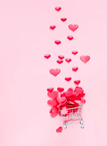 ピンクの背景にたくさんの心でいっぱいのトロリーショッピングカート — ストック写真