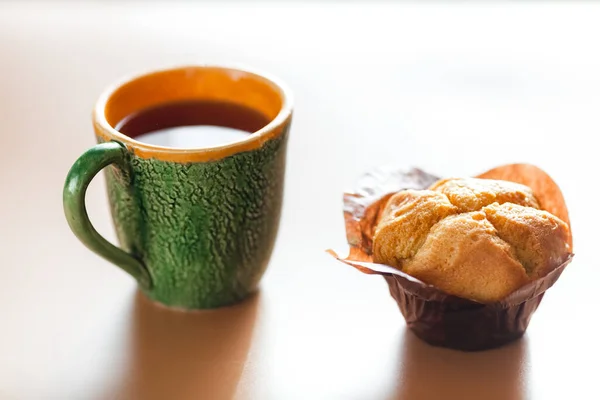 Cup of coffee and delicious fresh muffin on table — Stock Photo, Image