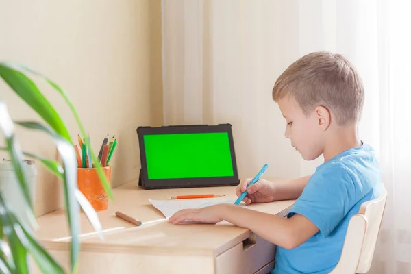 Gambar anak sekolah yang cerdas, tablet dengan layar hijau tetap di atas meja — Stok Foto