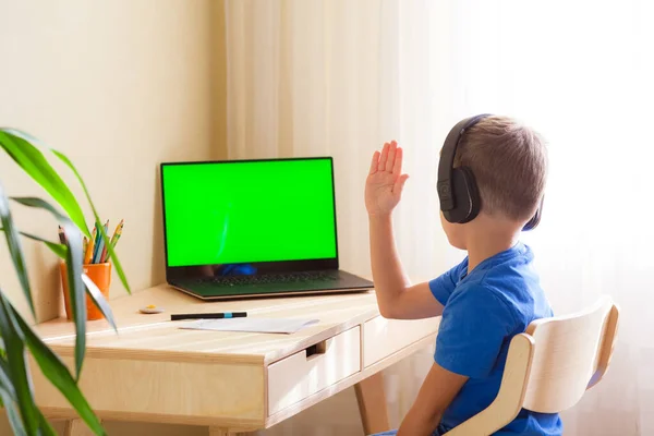 똑똑 한 남학생 이 책상에 앉아 컴퓨터를 봅니다. 아이가 손을 잡고 대답을 한다. — 스톡 사진