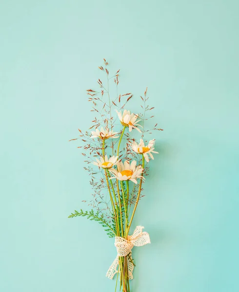 Ramo de flores de manzanilla con césped rural sobre fondo turquesa. Concepto minimalista. —  Fotos de Stock