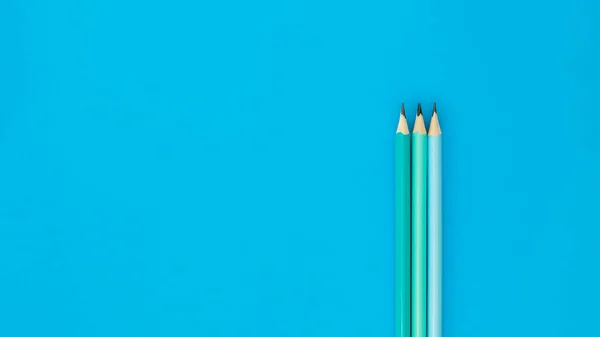 Tree pencils on blue background with copyspace — Φωτογραφία Αρχείου