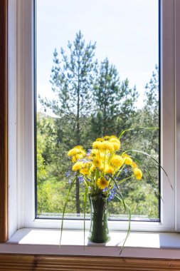 Kil vazodaki sarı karahindiba buketi kırsal alandaki pencerenin kenarında duruyor.