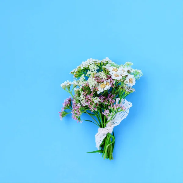 Gemütlicher Strauß ländlicher Blumen auf blauem Hintergrund mit Kopierraum. Minimalistisches Konzept. — Stockfoto