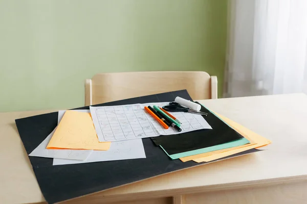 Lembaran kertas berwarna, sketsa permainan papan, pena berwarna dan gunting di atas meja — Stok Foto