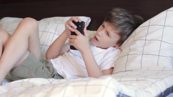 携帯電話を見ている間に男の子があくびをしている. — ストック動画
