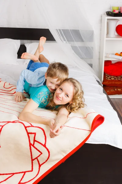 Young woman with her son laying on bed — Stock Photo, Image
